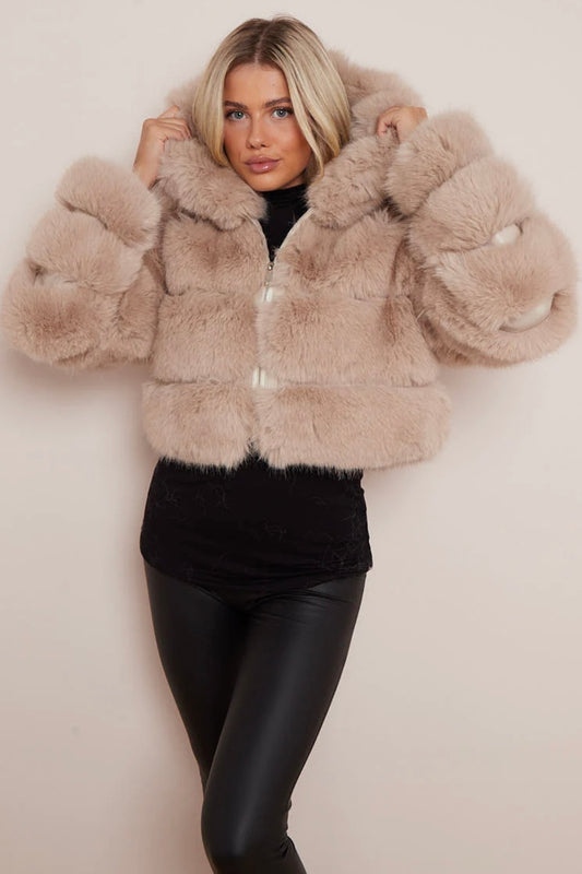 A model wearing a beige cropped faux fur hood coat with a snuggly hood, paired with black leggings.