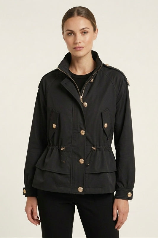 A woman modeling a black peplum-style utility jacket with gold-tone buttons and a high collar, set against a plain light background.
