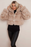 A model wearing a beige cropped faux fur hood coat with a snuggly hood, paired with black leggings.