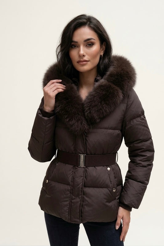 A woman wearing a dark brown puffer jacket with a large brown fur-trimmed collar and a matching belt, photographed against a plain light background.