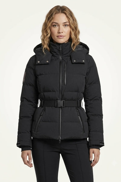A woman modeling a black hooded puffer jacket with a front zipper, snap details on the chest, and a matching black belt, set against a plain off-white studio background.