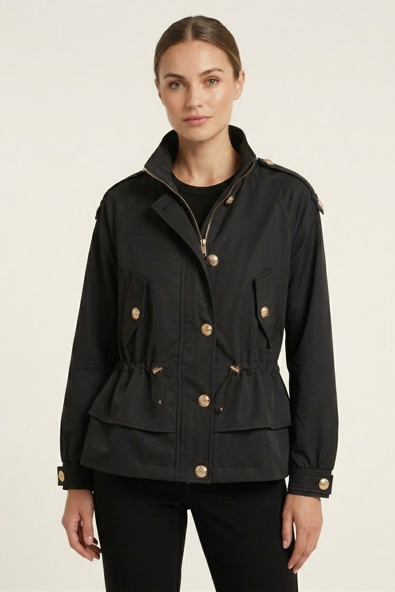 A woman modeling a black peplum-style utility jacket with gold-tone buttons and a high collar, set against a plain light background.